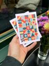 Herr Menig Junior children's optician postcards held by a hand coming from out of frame in a cozy setting