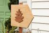 Wooden wayfinding post with a pinecone logo on it in front of a white mansion at Pinecone Childcare in Portland, Oregon.