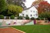 View of Pinecone Childcare in Portland, Oregon with the garden area in front, a colorful mural and a white mansion with trees around.