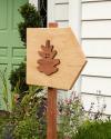 A wooden wayfinding post with a pinecone logo design in front of a house at Pinecone Childcare in Portland, Oregon.