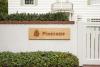 Wooden entrance sign with a pinecone logo on a garden wall at Pinecone Childcare in Portland, Oregon.